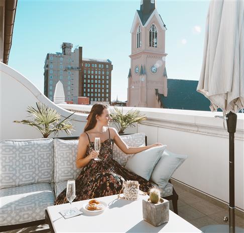 Woman sitting outside at Hotel Bennett's King's Club holding a glass of champagne