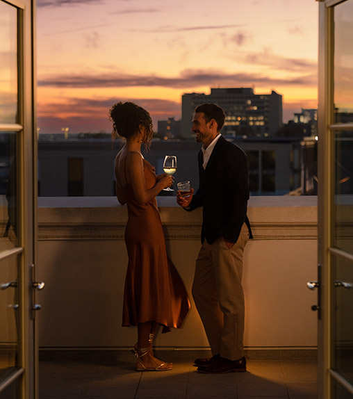 couple drinking on balcony overlooking the city