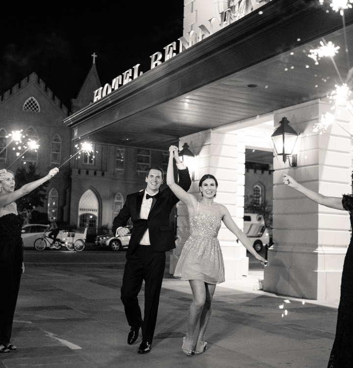 Black and white photo of couple kissing surrounded by guests with sparklers