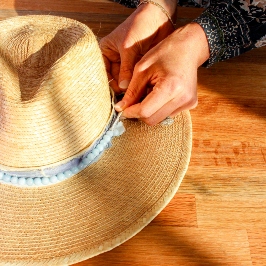 Straw hat being decorated with pastel blue felt garland